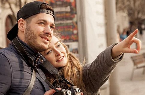 Pareja observando un rumbo en común mientras ella señala hacia adelante apoyada en su pareja